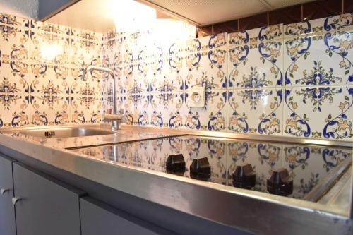 - une cuisine avec un évier et du carrelage bleu et blanc dans l'établissement Appartement 3 pièces GRUISSAN GN380-C67, à Gruissan