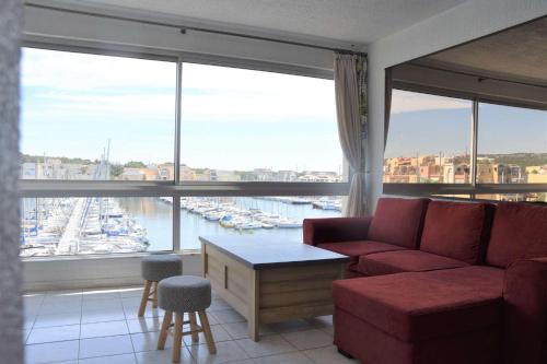 - un salon avec un canapé rouge et une grande fenêtre dans l'établissement Appartement 3 pièces GRUISSAN GN380-C67, à Gruissan