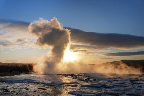 a geyser eruption with the sun in the background at Black diamond villa in Mosfellsbær