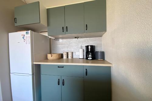 La cuisine est équipée de placards bleus et d'un réfrigérateur blanc. dans l'établissement nest of sweetness on the port side, à Frontignan