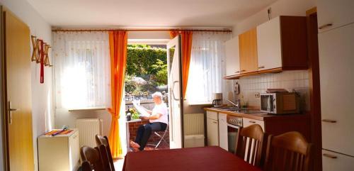 a woman sitting in a kitchen looking out the door at Ferienwohnung Schlichting in Travemünde