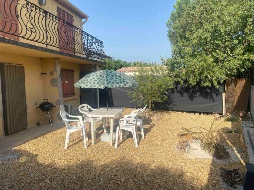 un patio avec une table, des chaises et un parasol dans l'établissement Studio en rez-de-maison, au Muy
