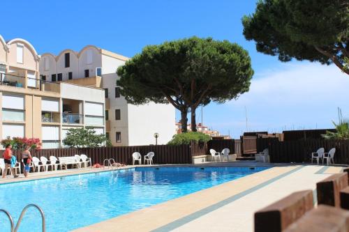 - une piscine avec des tables et des chaises à côté d'un bâtiment dans l'établissement Appartement Studio 2 couchages GRUISSAN GN400-236, à Gruissan