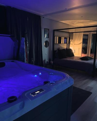 - une salle de bains avec une baignoire bleue dans une chambre avec un lit dans l'établissement LS normandie, à Saint-Pois