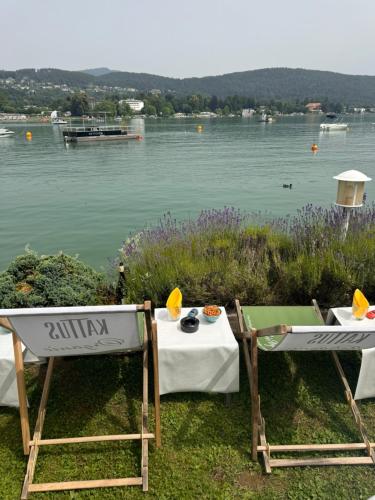 two tables and chairs with a view of a lake at Strandhaus am Wörthersee in Velden am Wörthersee