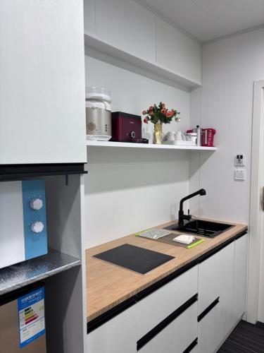 a kitchen with white cabinets and a wooden counter top at Amber Lake D in Auckland