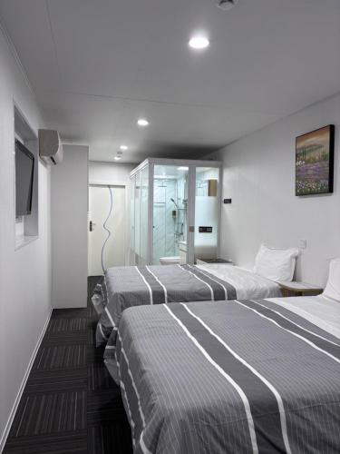 three beds in a hotel room with a tv at Amber Lake D in Auckland