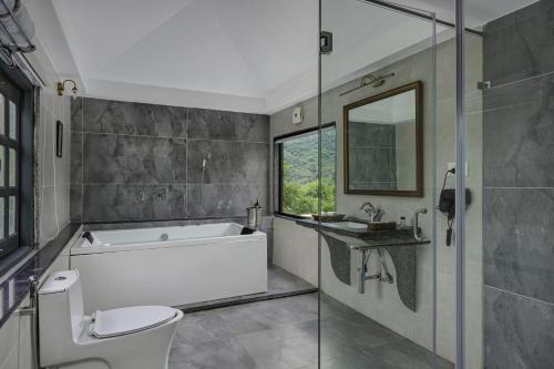 a bathroom with a tub and a toilet and a sink at Anandam - A Luxury Resort in Udaipur in Udaipur