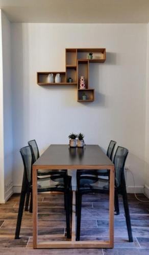 une table de salle à manger avec des chaises noires et une étagère dans l'établissement Grand Apt 4 Chambres - Terrasse - Moderne - Centre d'Evry, Évry-Courcouronnes