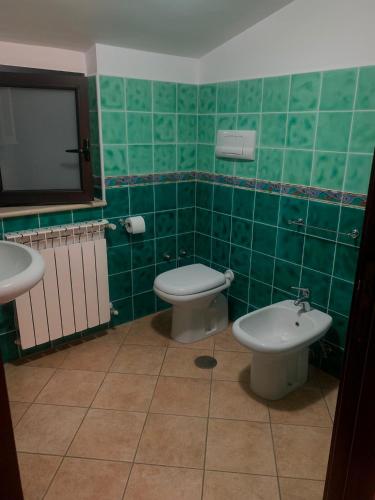 a green tiled bathroom with a toilet and a sink at Casa vacanze Apollonia in Marina di Camerota