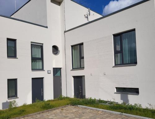 a white building with black doors and windows at Hafen 15 - Ihre Ferienwohnung im Hafen am Geiseltalsee in Mücheln