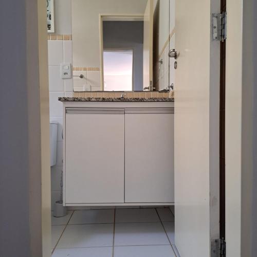a white bathroom with a sink and a mirror at Apartamento Villagio Olímpia in Olímpia