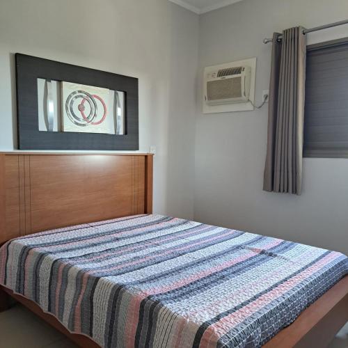 a bedroom with a bed with a striped blanket on it at Apartamento Villagio Olímpia in Olímpia