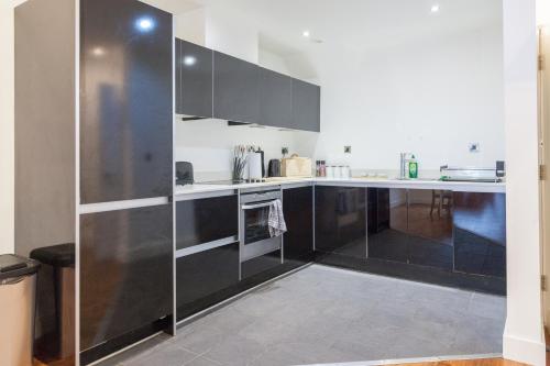 a kitchen with black and white cabinets and appliances at City Centre Penthouse Apartment in Leeds