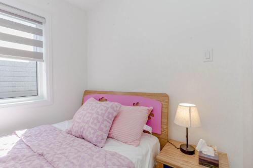 a bed with pink and white sheets and a table with a lamp at Amazing Home in Niagra Region in Thorold