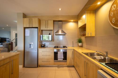 a kitchen with wooden cabinets and a stainless steel refrigerator at Kaya Anvi - Plettenberg Bay in Plettenberg Bay