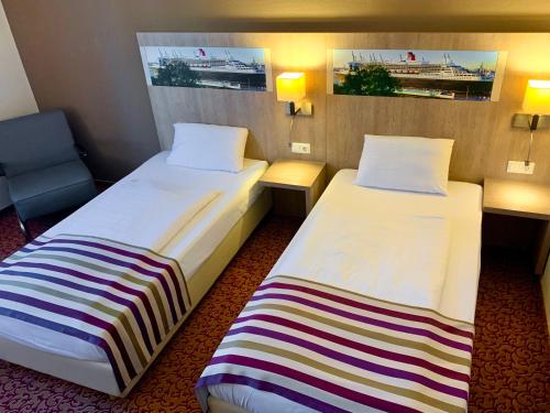 a room with two beds and a chair at Mercure Hotel Hamburg am Volkspark in Hamburg