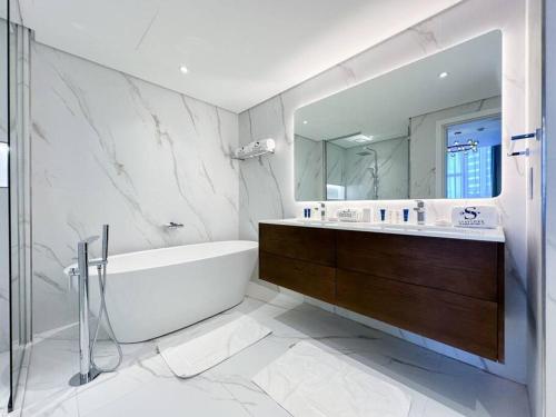 a bathroom with a tub and a sink and a mirror at Fantastic flat in TiaraResidence in Dubai