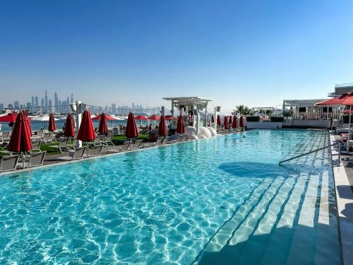 a large swimming pool with chairs and red umbrellas at Spacious beachfront 2 bedroom apartment - The 8 in Dubai
