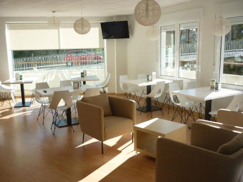 un comedor con mesas, sillas y ventanas en Pensión-Albergue Puente Ribeira, en Sarria