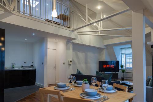 a dining room and living room with a table and chairs at City Centre Penthouse Apartment in Leeds
