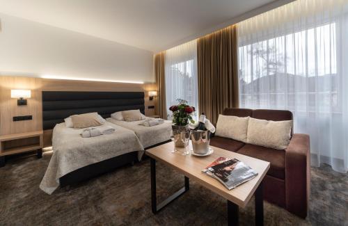 a bedroom with a bed and a couch and a table at Hotel Solar in Szczawnica