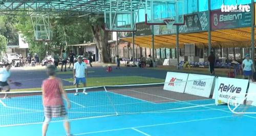 a group of people playing tennis on a tennis court at HOTEL MOTeL Đồng Khởi in Giồng Tú Ðiền