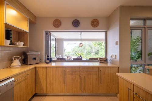 a kitchen with wooden cabinets and a window at Kaya Anvi - Plettenberg Bay in Plettenberg Bay