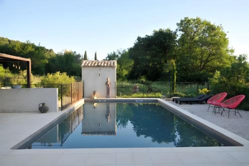- une piscine dans une arrière-cour entourée de chaises rouges dans l'établissement Mas Boho - 16th century eclectic, à Entrechaux