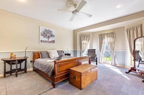a bedroom with a bed and a desk and a fan at Dulguigan Downs Farm House in Condong