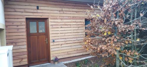a wooden building with a door next to a tree at Selina in Janske Lazne