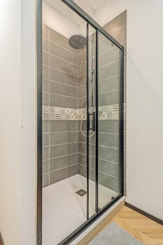 La salle de bains est pourvue d'une douche avec des portes en verre. dans l'établissement Ty Coz T3 tout confort, à La Richardais