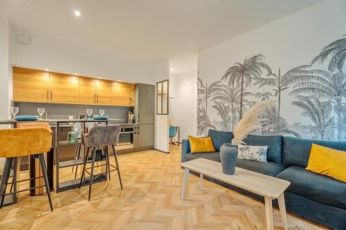 un salon avec un canapé bleu et une cuisine dans l'établissement Ty Coz T3 tout confort, à La Richardais