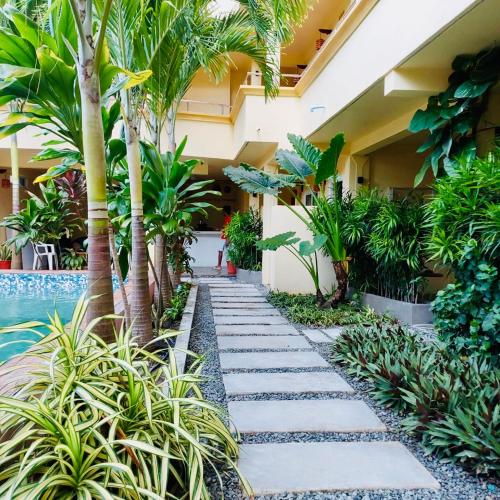 a walkway in front of a building with palm trees at Sorenzo Maldives in Thoddoo