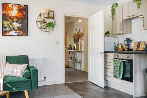 a living room with a green chair and a kitchen at Affordable 1 & 2 Bed Apartments in Slough, Great Heathrow Location in Colnbrook