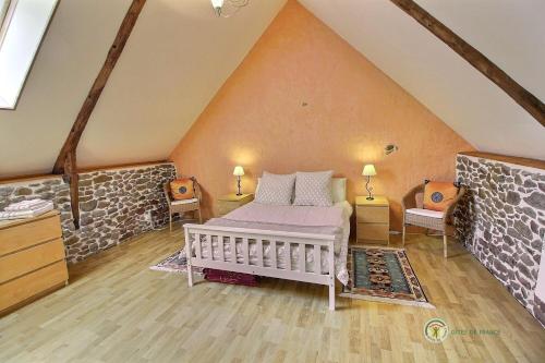 - une chambre mansardée avec un lit et deux chaises dans l'établissement Stable cottage, à Pleudihen-sur-Rance