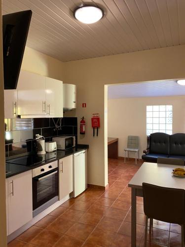 une cuisine avec des armoires blanches et une table dans une pièce dans l'établissement caminho da praia da maiata, à Porto da Cruz