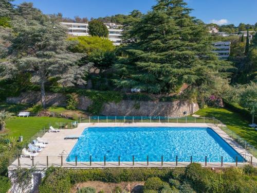- une vue sur la grande piscine bordée d'arbres dans l'établissement Riviera Escape – Sea View, Pool & Tennis, à Cannes