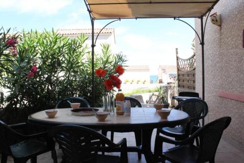- une table et des chaises sur une terrasse avec un parasol dans l'établissement SP480-191 Mais 2 pièces mezzanine SAINT PIERRE LA MER, à Saint Pierre La Mer
