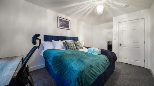 a bedroom with a bed with a blue comforter at Affordable 1 & 2 Bed Apartments in Slough, Great Heathrow Location in Colnbrook