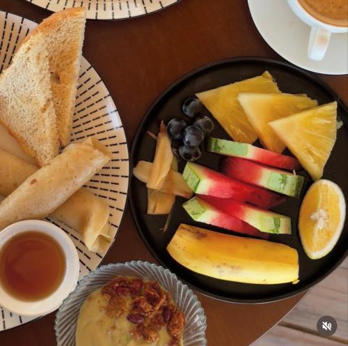 a plate of food with fruit and bread on a table at Mia Boutique Hotel in Michamvi