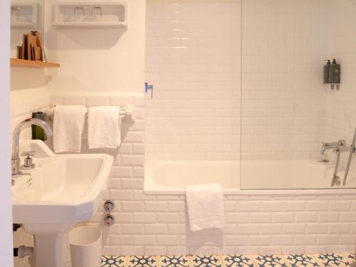 a white bathroom with a tub and a sink at Hostal Empúries in L'Escala