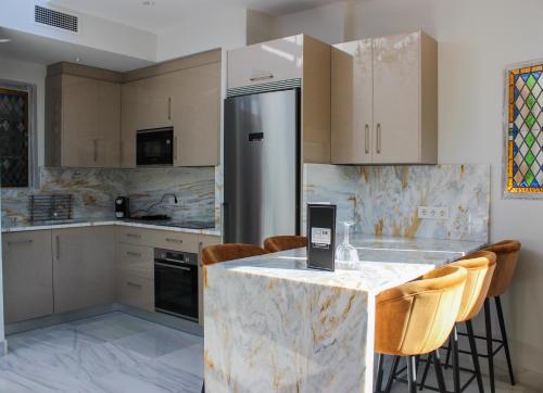 a kitchen with a refrigerator and a counter with chairs at BiBo Suites Real Chancilleria in Granada