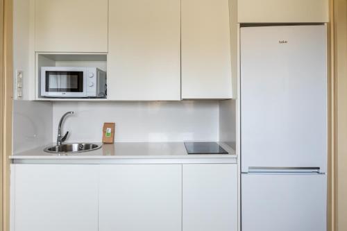 a white kitchen with a sink and a microwave at Resa Emperador Carlos V in Granada