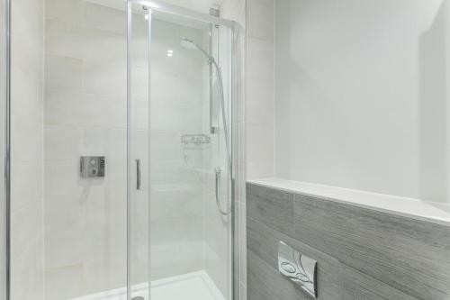 a bathroom with a shower with a glass door at 2 Middlecombe - Luxury Apartment at Byron Woolacombe, only 4 minute walk to Woolacombe Beach! in Woolacombe