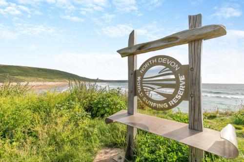 a sign at the beach with the ocean in the background at 2 Middlecombe - Luxury Apartment at Byron Woolacombe, only 4 minute walk to Woolacombe Beach! in Woolacombe