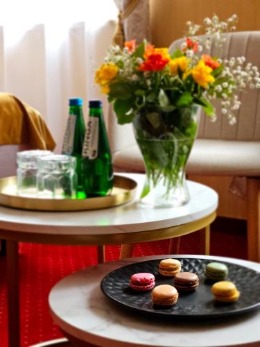 a table with a plate of cookies and a vase of flowers at Hotel Galicja SPA Wieliczka in Wieliczka