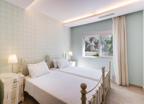 una camera da letto con un letto bianco e una finestra di Maria by Vintage Travel a Città di Lefkada