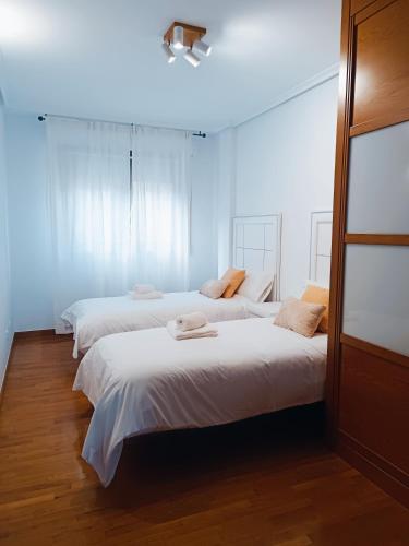 three beds in a room with white walls and wood floors at Apartamento San Pelayo, LA PICUDA in San Vicente de la Sonsierra