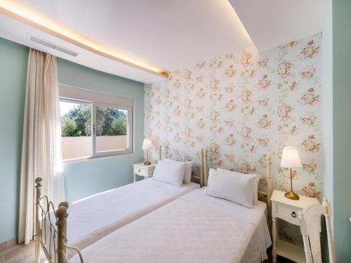 2 letti in una camera da letto con carta da parati floreale di Leda by Vintage Travel a Città di Lefkada